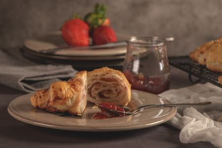 Baked croissants with strawberry jam on a kitchen countertop.の写真素材