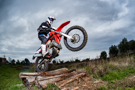 Enduro bike rider in action. Obstacle overcome on mud and grass terrain.の写真素材