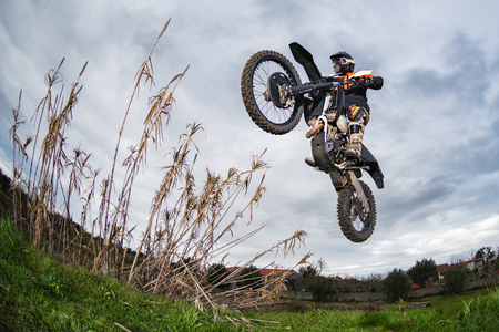 Enduro bike rider in action. Jump on mud and grass terrain.の写真素材