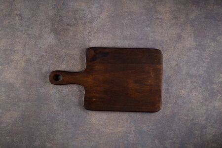 Top view of wooden cutting board on old stone countertop.