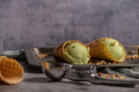 Balls of pistachio ice cream in waffle cones on a dark background.の写真素材