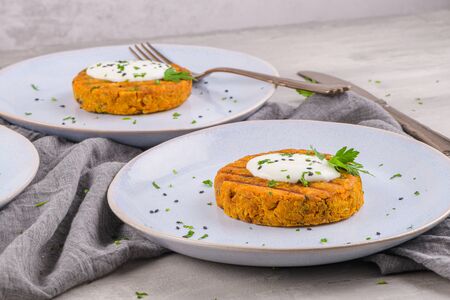 Grilled veggie burgers with chickpeas and vegetables and parsley leaves on ceramic plates.