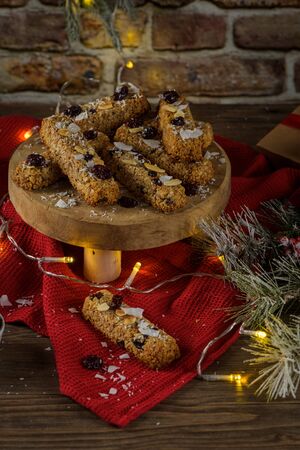 Cereal bars with almonds, coconut and cranberries on a Christmas season table decorated with lights.の写真素材