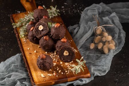 Dark chocolate truffles with hazelnuts over wooden cutting board.