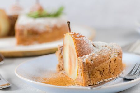 Delicious cake slice with pear, ginger and cinnamon on a plate in a dark kitchen counter.の写真素材