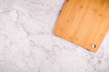Top view of wooden cutting board on a gray marble background with space for text.