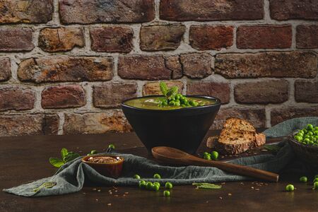 Green pea soup with linseed and pumpkin and sunflower seeds on a rustic kitchen countertop.の写真素材