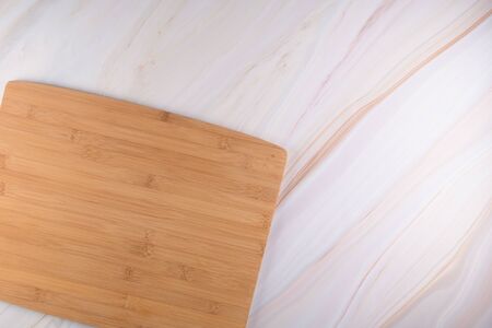 Top view of wooden cutting board on a gray marble background with space for text.