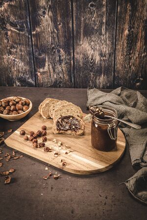 Vegan chocolate spread made of organic almond butter and organic cacao and honey, on dark rustic kitchen counter top.の写真素材
