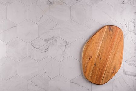 Top view of wooden cutting board on modern hexagonal pattern marble stone countertop.の写真素材