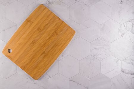 Top view of wooden cutting board on modern hexagonal pattern marble stone countertop.