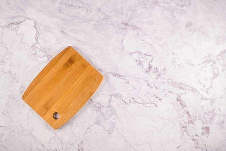 Top view of wooden cutting board on a gray marble background with space for text.
