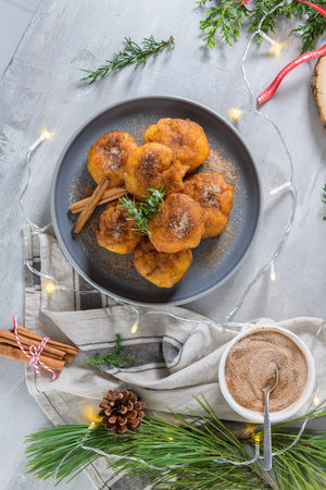 Traditional portuguese Christmas sweets Sonhos with sugar and cinnamon on kitchen countertop.