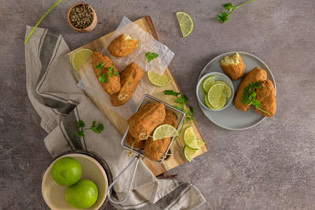 Meat croquets with rosemary leaves and lemons on wooden cutting board in a kitchen counter top.