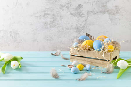 Easter blue and white eggs in wooden box and white tulips.の写真素材