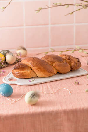 Portuguese traditional Easter cake. Folar with eggs on easter table. Blossom flowers and colorful...