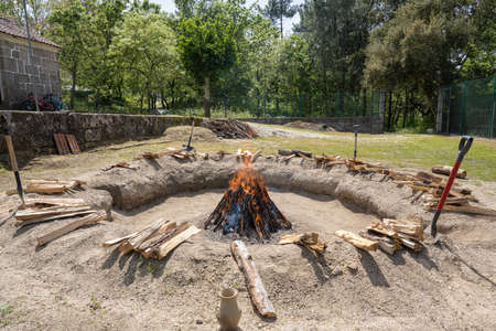 AMARANTE, PORTUGAL - APRIL 30: Bonfire with the pieces of clay stacked during the process of cooking the black clay of Gondar on April 30, 2022 in Amarante, Portugal.のeditorial素材