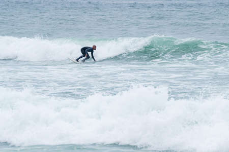 Surfer riding waves with a soft board in Furadouro beach, Portugal. Men catching waves in ocean. Surfing action water board sport.の写真素材