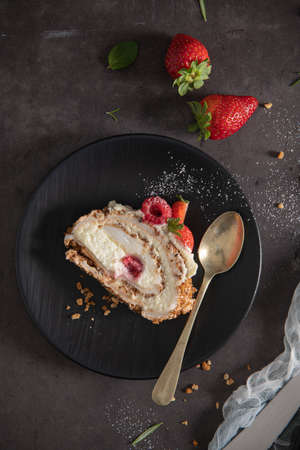 Meringue roll cake with cream, raspberries. Roulade, summer dessert served in ceramic plate.の写真素材