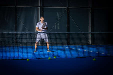 Sporty european man in white t-shirt playing padel tennis indoorの写真素材