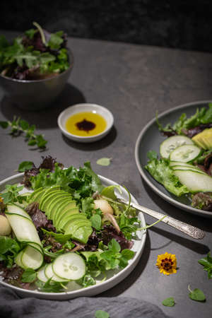 Fresh summer salad with cucumber, melon, avocado and fresh oregano served on ceramic plates.の写真素材