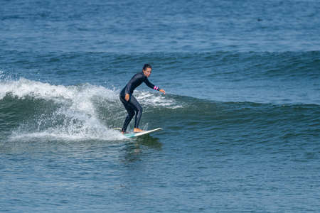 Surfer girl riding a wave with on a hot sunny day in Furadouro beach, Ovar - Portugal.の写真素材