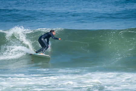Surfer girl riding a wave with on a hot sunny day in Furadouro beach, Ovar - Portugal.