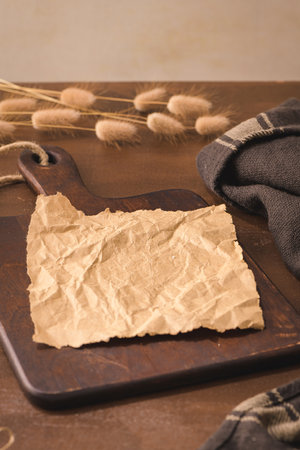 Crumpled paper and wooden cutting board on brown moody and rustic kitchen countertop.の写真素材