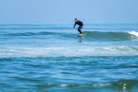 A middle aged man doing some foil surfing or hydrofoil surfing in the sea on a bright sunny day.の写真素材