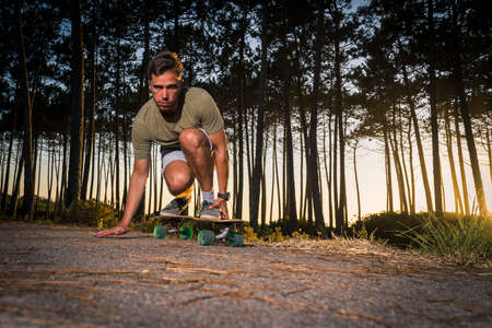 Surf skater rolling by the pine forest at sunset in Maceda, Ovar - Portugal.