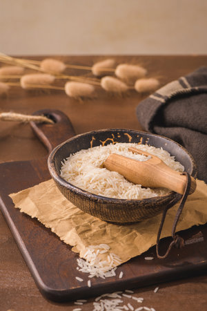 Basmati rice in ceramic bowl with wooden scoop on rustic countertop.の写真素材