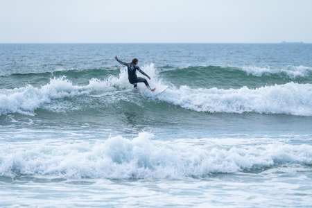 Surfer girl riding a wave on a cloudy afternoon at Torreira beach, Murtosa - Portugal.