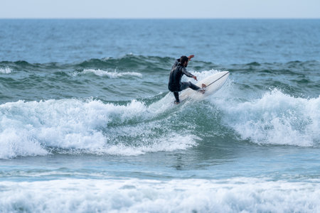 Surfer riding a wave on a cloudy afternoon at Torreira beach, Murtosa - Portugal.