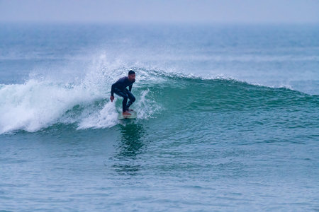 Brazilian surfer in action in the waves of the Atlantic coast of Portugal. On a cloudy morning at...
