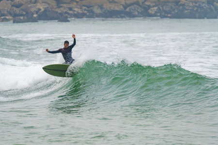 Brazilian surfer in action in the waves of the Atlantic coast of Portugal. On a cloudy morning at...