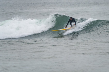 Surfer in action on the ocean waves on a cloudy morning at Furadouro beach, Ovar - Portugal.の写真素材