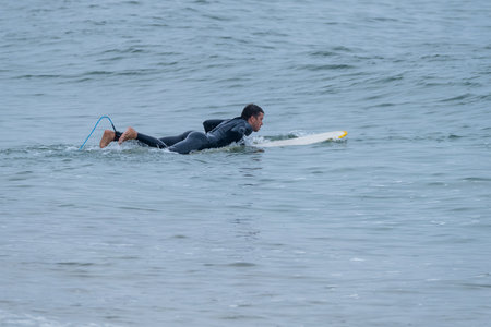 Surfer on longboard over the water on a cloudy morning at Furadouro beach, Ovar - Portugal.