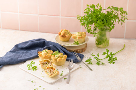 Chicken pies and parsley leaves on white ceramic dishes in a kitchen counter top.