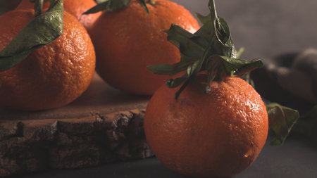 Fresh mandarin oranges or tangerines with leaves on textured dark backgroundの写真素材