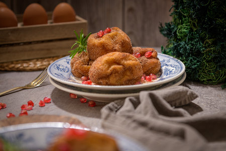 Rabanadas poveiras with sugar and cinnamon and some pomegranate seeds on a rustic kitchen countertop during the Christmas season.の写真素材