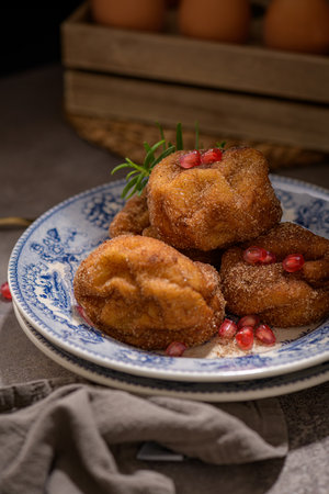 Rabanadas poveiras with sugar and cinnamon and some pomegranate seeds on a rustic kitchen countertop...