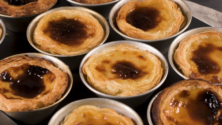 Rows of freshly cooked egg tarts, traditional Portuguese dessert, pastel de nata, custard tarts on...