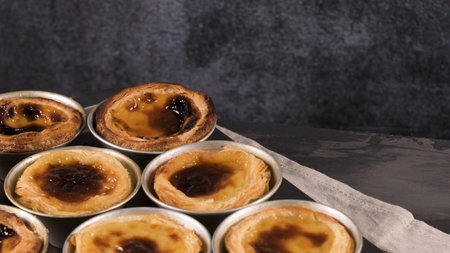 Rows of freshly cooked egg tarts, traditional portuguese dessert, pastel de nata, custard tarts on metal tray.の写真素材