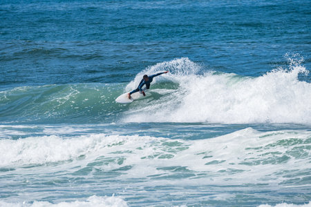 Young athletic surfer rides the wave at Furadouro Beach in Ovar, Portugal.
