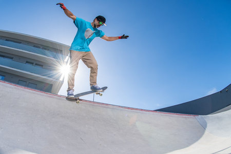 Skateboarder doing backside five-o grind trick in concrete skatepark.