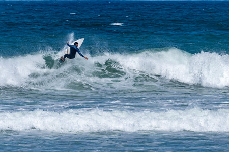 Surfer riding waves in Furadouro Beach, Portugal. Men catching waves in ocean. Surfing action water board sport. people water sport lessons and beach swimming activity on summer vacation.の写真素材