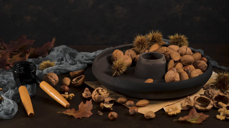Autumn dry fruits on table with a nut cracker tool and a black ceramic plate.の写真素材