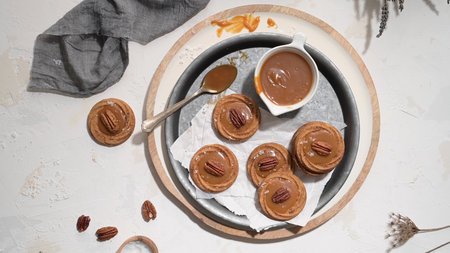 Caramel cookies with pecan nuts served on roud plates, in the kitchen after baking.の写真素材