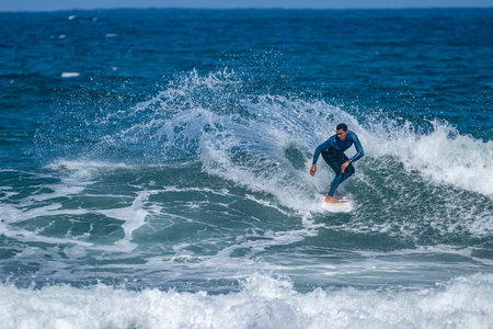 Surfer riding waves in Furadouro Beach, Portugal. Men catching waves in ocean. Surfing action water board sport. people water sport lessons and beach swimming activity on summer vacation.の写真素材