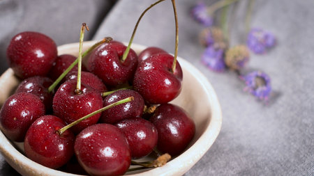 Red fresh cherries in bowls and a bunch of cherries on the table.